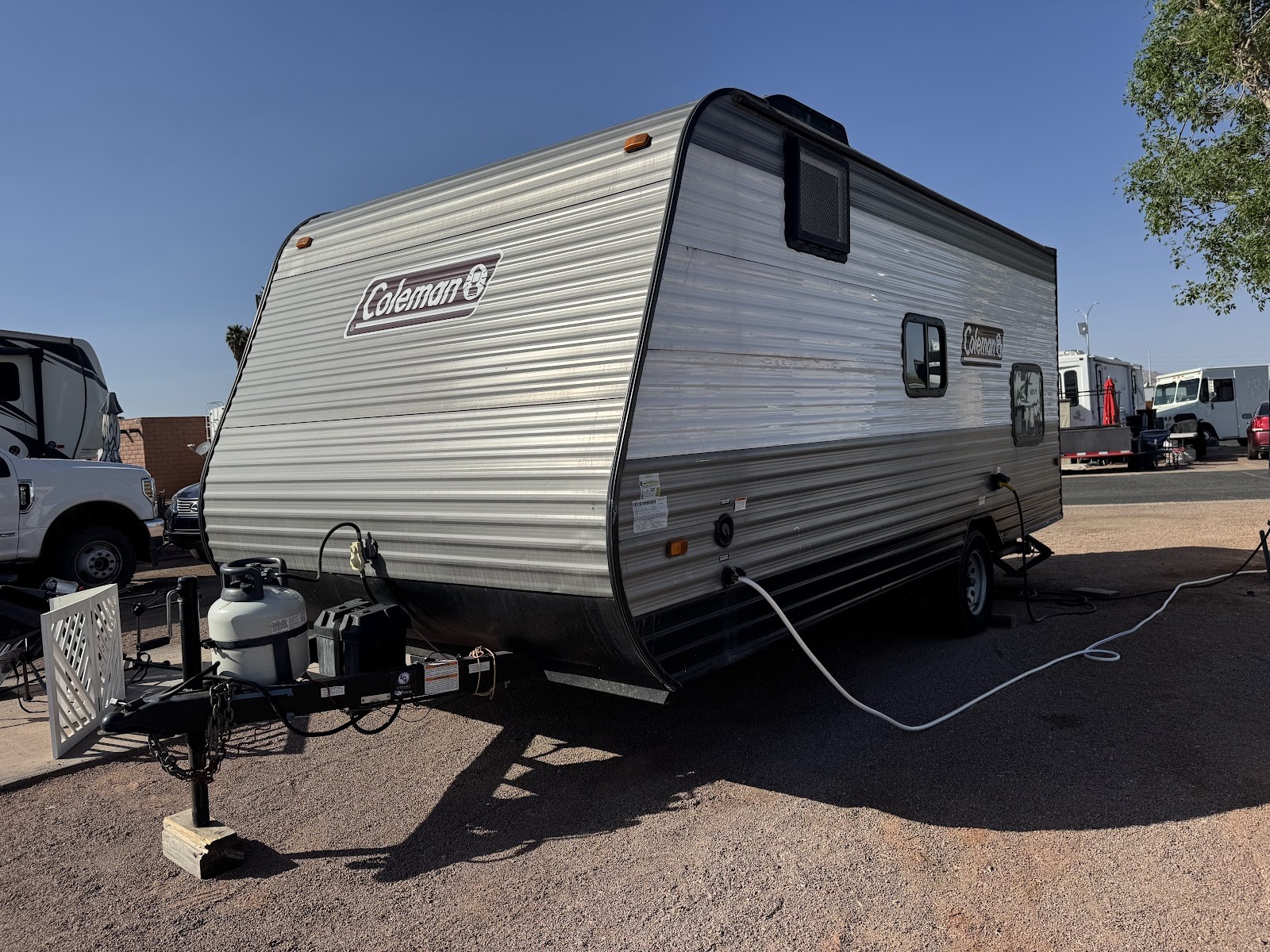Coleman travel trailer RV parked at an RV lot, plugged in with propane tank